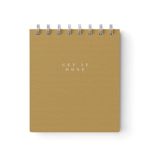 May include: A notepad with a textured, golden-brown cover and silver spiral binding. The text "GET IT DONE" is printed in silver on the front. The notepad is rectangular and set against a white background.