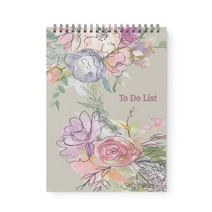May include: A spiral-bound notepad with a beige cover featuring watercolor floral illustrations in pink, purple, and blue. The words "To Do List" are printed in a soft, muted pink. The design includes delicate line drawings of flowers and leaves.