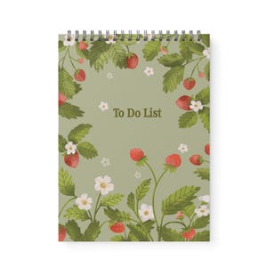 May include: A spiral-bound notepad with a green background and a strawberry design. The cover features red strawberries, white flowers, and green leaves. The words "To Do List" are printed in the center.