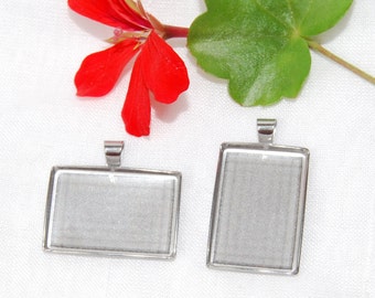 May include: Two silver-toned metal picture frames with clear glass inserts. The frames are rectangular and have a bail at the top for hanging.