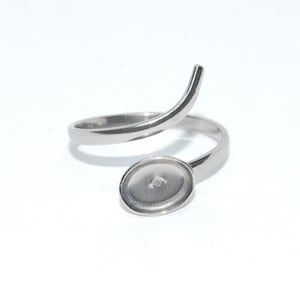 Puede incluir: Un anillo de plata con un engaste redondo y plano. El anillo está diseñado para envolverse alrededor del dedo.