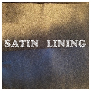 May include: Close-up of a fabric swatch with the words "SATIN LINING" in white, outlined in small white circles. The fabric is a dark blue color on the bottom and a gold color on the top.