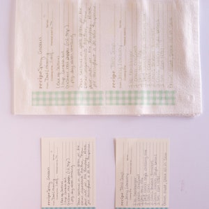 May include: Three recipe cards with a green and white checkered border. The cards are for Spicy Crackers, Taco Soup, and Spicy Crackers. The recipe cards are written in cursive handwriting.