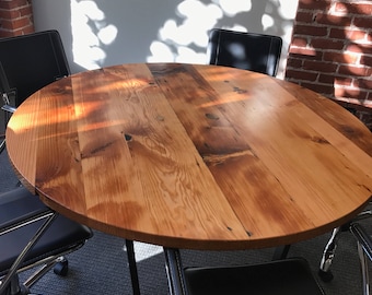 May include: A round wooden table with a natural wood finish and black metal legs. The table is surrounded by four black leather chairs with chrome bases.