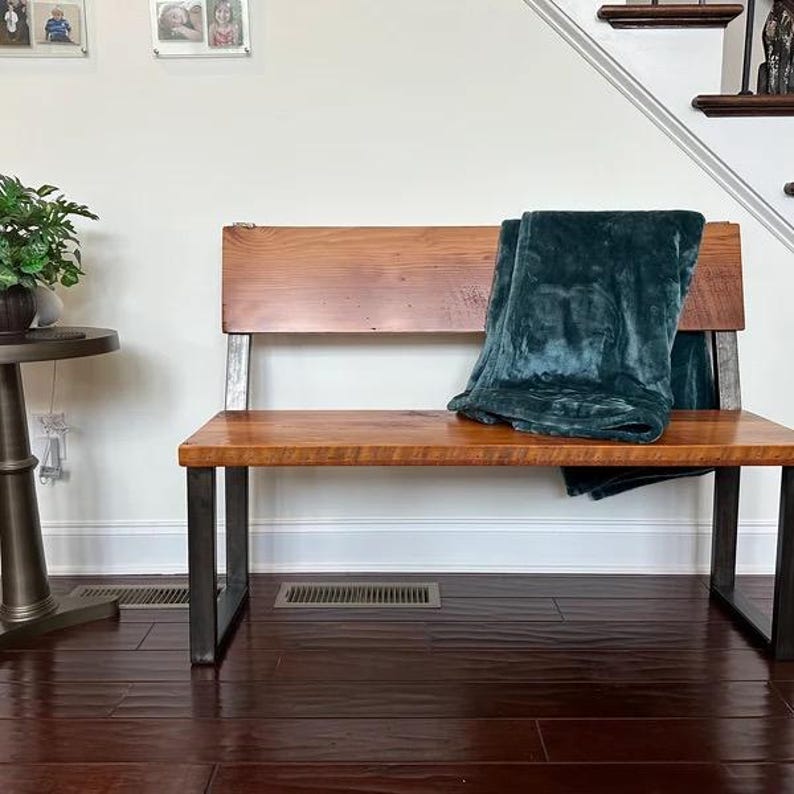 May include: A wooden bench with a teal blanket on top. The bench has a metal frame and a wooden seat and back.