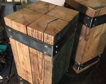 May include: Two rectangular wooden pillars featuring a natural light brown grain and visible cracks on the top surface. Each pillar is reinforced with two horizontal dark gray metal bands secured by silver rivets at the corners and sides.