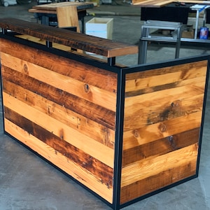 May include: A rustic wooden reception desk with a black metal frame. The desk is made of reclaimed wood with a variety of wood tones and textures. The desk has a simple, modern design and would be a great addition to any office or retail space.