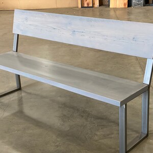 May include: A gray wooden bench with a metal frame. The bench has a simple design with a rectangular seat and back.