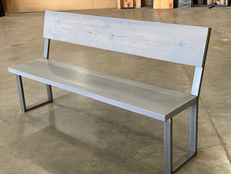 May include: A gray wooden bench with a metal frame. The bench has a simple design with a rectangular seat and back.