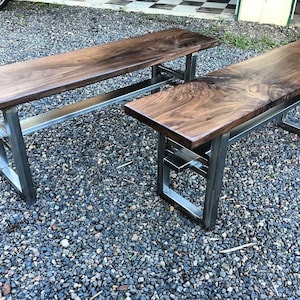 May include: Two wooden benches with metal frames. The benches are made of dark wood and have a natural finish. The metal frames are silver and have a simple design.