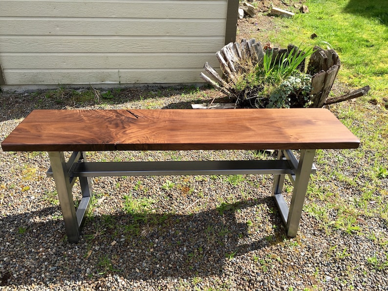 May include: A wooden bench with a dark brown top and a metal frame. The bench has a shelf underneath the top.