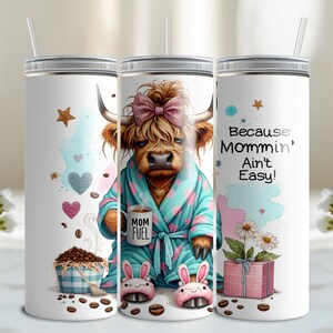 A funny Highland cow in a polka-dot robe, pink bunny slippers, and coquette bow holding a "Mom Fuel" mug, surrounded by coffee beans, glitter hearts, daisies, and a pink gift box. Text reads, "Because Mommin’ Ain’t Easy!" on a playful background.