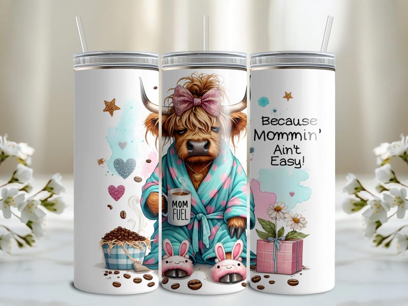 A funny Highland cow in a polka-dot robe, pink bunny slippers, and coquette bow holding a "Mom Fuel" mug, surrounded by coffee beans, glitter hearts, daisies, and a pink gift box. Text reads, "Because Mommin’ Ain’t Easy!" on a playful background.