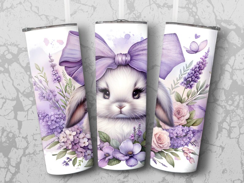 A beautiful 20 oz tumbler wrap featuring an adorable white Easter bunny with big, expressive eyes, wearing a large purple bow. Surrounded by soft pastel florals, lavender, and butterflies in a dreamy watercolor style on a white background