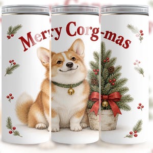 May include: A white cylindrical tumbler featuring a tan and white Corgi dog wearing a green collar with a gold bell. The design includes a small potted Christmas tree with a red bow and the red text Merry Corg-mas, accented by holly sprigs.