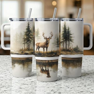 May include: A white stainless steel travel mug with a brown and green forest scene and a deer with antlers. The mug has a lid and a straw.