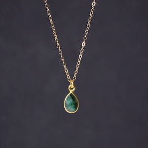 Puede incluir: Un collar de cadena de oro con un colgante de piedra preciosa verde en forma de lágrima.