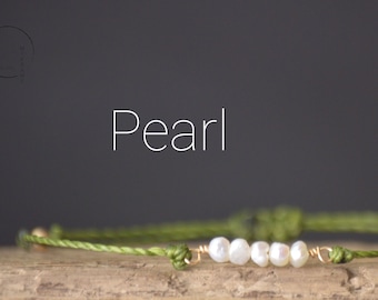 May include: A green string bracelet with a row of five white pearls.