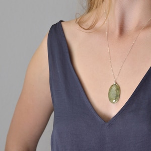 Puede incluir: Un collar de cadena de plata con un colgante de piedra preciosa verde de forma ovalada grande.
