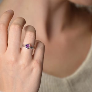 May include: A silver ring with a purple heart-shaped gemstone.