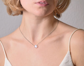 May include: A simple silver necklace with a single, large, iridescent pearl pendant.