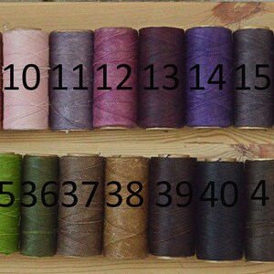 May include: A wooden board with 50 spools of thread in various colors. The spools are numbered 1 through 50.