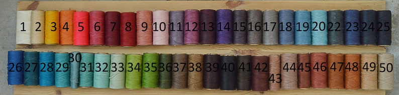 May include: A wooden board with 50 spools of thread in various colors. The spools are numbered 1 through 50.