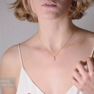 May include: A gold chain necklace with a small oval-shaped pendant. The model is wearing a 16 inch / 40 cm length chain.