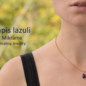 May include: A gold chain necklace with a teardrop-shaped lapis lazuli pendant. The necklace is worn by a person with a black tank top. The text "Lapis lazuli Mikrame Healing Jewelry" is visible in the image.