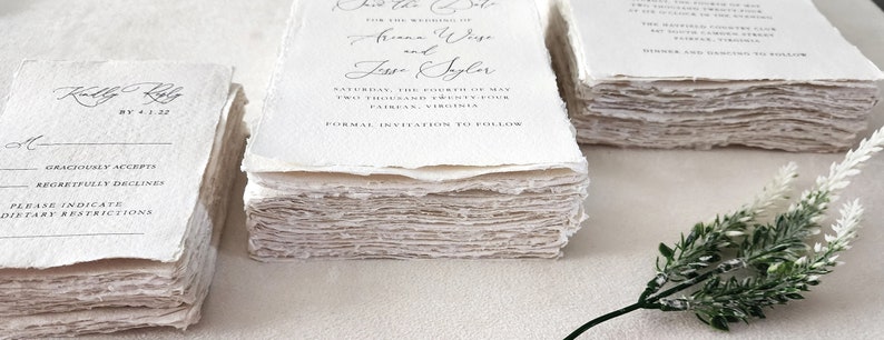 Stacks of custom wedding invitations, RSVP and details cards printed on handmade cotton rag deckle edge paper, showing the natural texture and torn edges.