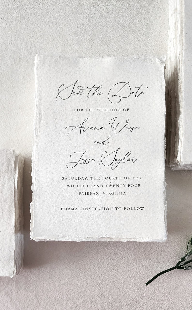 Custom save the date printed on handmade cotton rag deckle edge paper with elegant black calligraphy, showing the natural paper texture and torn edges.