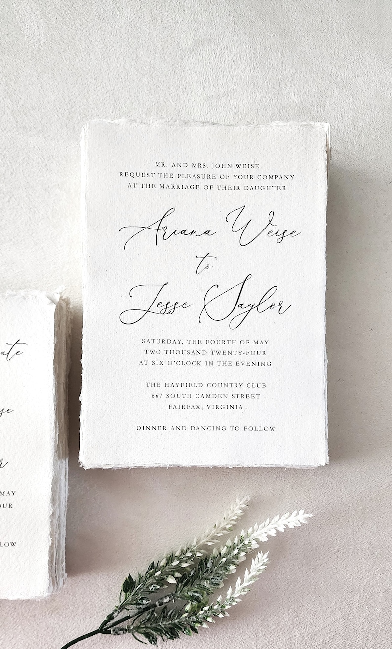Custom wedding invitation printed on handmade cotton rag deckle edge paper with elegant black calligraphy and classic typography, showing the natural paper texture and torn edges.