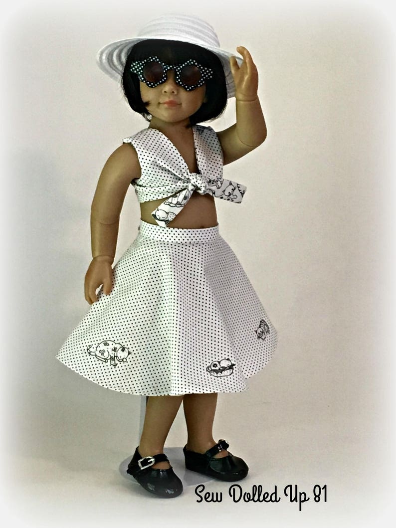 May include: A white doll wearing a white polka dot crop top with a black bow, a white polka dot skirt with black designs, a white hat, and black sunglasses. The doll is standing on a white stand. The text "Sew Dolled Up 81" is at the bottom of the image.