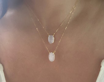 May include: A gold chain necklace with two oval-shaped white gemstone pendants.
