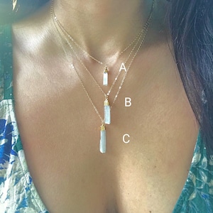 May include: Three gold necklaces of varying lengths, each with a light blue crystal pendant shaped like a long, thin rectangle. The pendants are labelled A, B, and C.