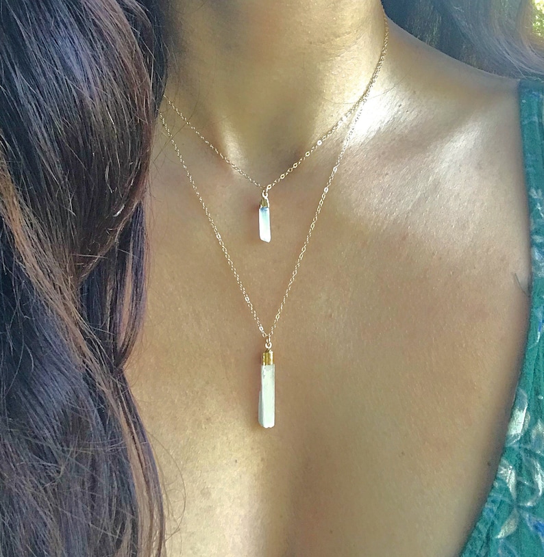 May include: A gold chain necklace with two white crystal pendants. The necklace is layered and features two different lengths of chain.