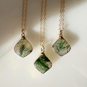 May include: Three gold necklaces with green and white agate stone pendants. Each pendant is a square with rounded corners.