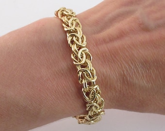May include: A gold chain bracelet with a woven design.