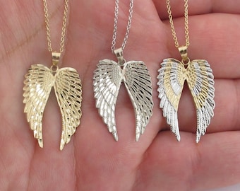 May include: Three angel wing necklaces with delicate chains. The wings are made of gold and silver metal and have a textured, diamond-like pattern.