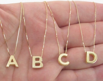 Op de afbeelding: Vier gouden kettingen met initiaal hangers. De hangers zijn in de vorm van de letters A, B, C en D.