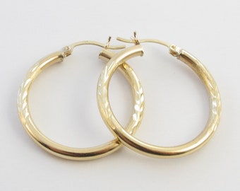 May include: A pair of gold hoop earrings with a textured design. The earrings are simple and elegant.