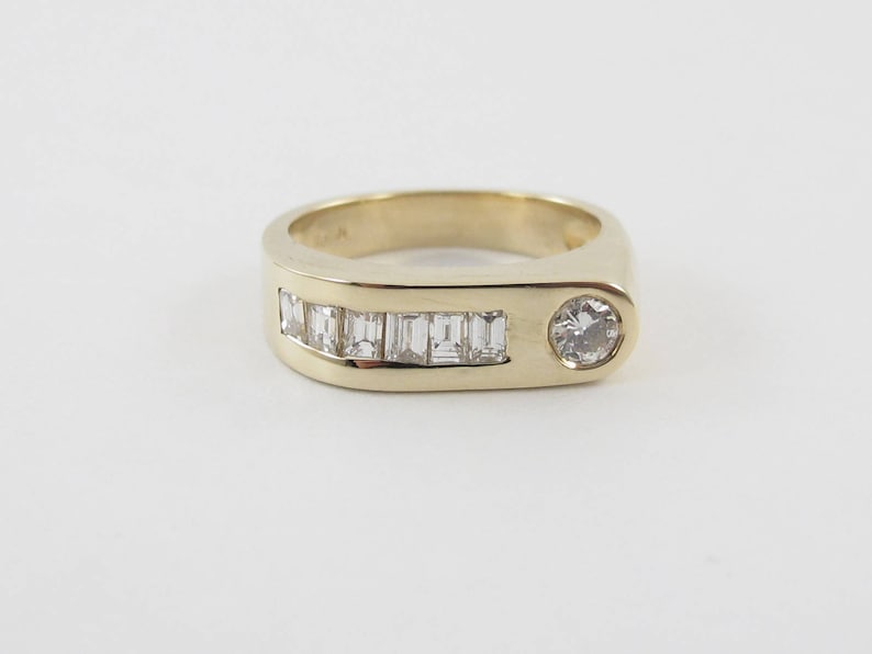 May include: A gold band ring with a single round diamond and a row of baguette diamonds set in a curved band.
