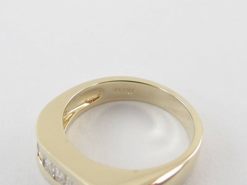 May include: A gold band ring with a row of small diamonds set into the band. The inside of the band is marked "14K 14".
