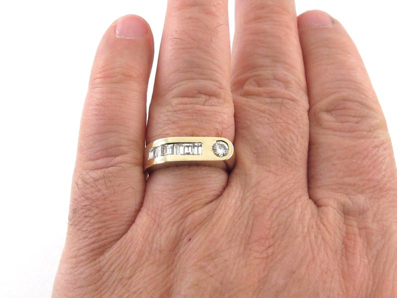 May include: A gold band ring with a single round diamond and a row of baguette diamonds.