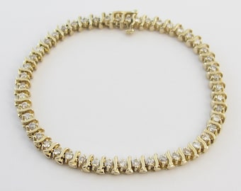 May include: A gold tennis bracelet with a row of small round diamonds set in a wavy pattern.