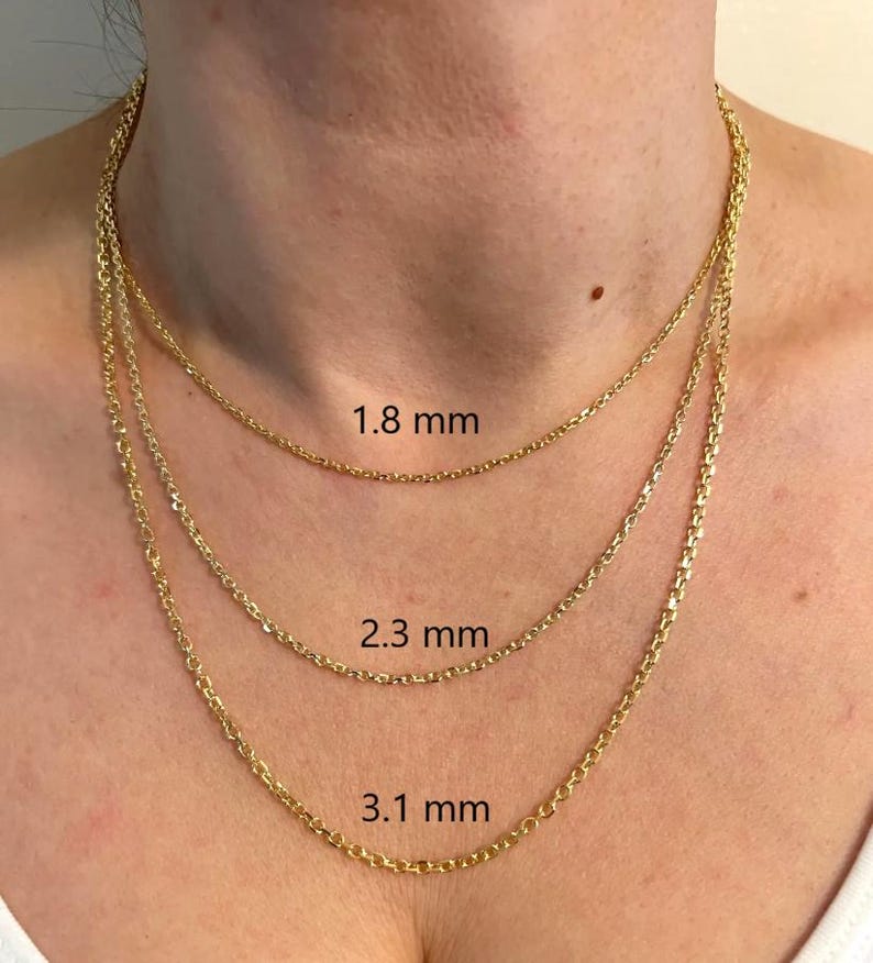 May include: Three gold-colored chain necklaces of varying thicknesses are displayed. The chains are 1.8 mm, 2.3 mm, and 3.1 mm thick. The necklaces are around a person's neck, showcasing the different chain styles and sizes.