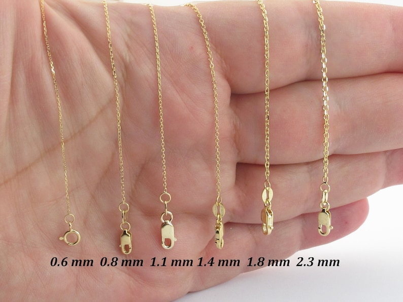 May include: A selection of gold necklaces with varying chain thicknesses, ranging from 0.6 mm to 2.3 mm. Each necklace is displayed with its clasp and measurement in millimeters.