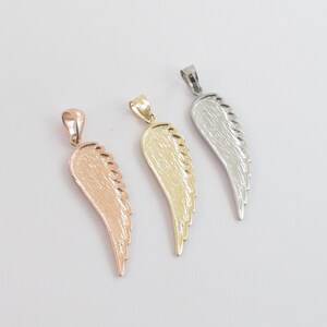 Op de afbeelding: Drie engelenvleugel hangers in verschillende metaal afwerkingen: goud, zilver en ros&eacute;goud. Elke hanger heeft een gedetailleerd vleugel ontwerp.