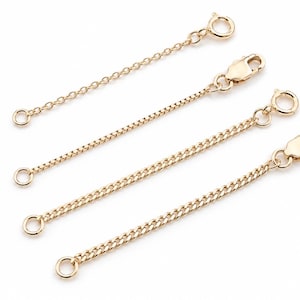 May include: Four gold-toned metal jewellery extender chains of varying lengths. Each chain features a small circular jump ring at one end and a lobster claw clasp at the other end, designed to add length to necklaces or bracelets.