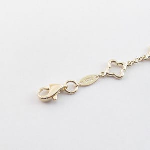 May include: Gold-toned bracelet with a clover design. The bracelet features a lobster clasp closure and a series of clover-shaped charms connected by small chain links. The background is plain white.